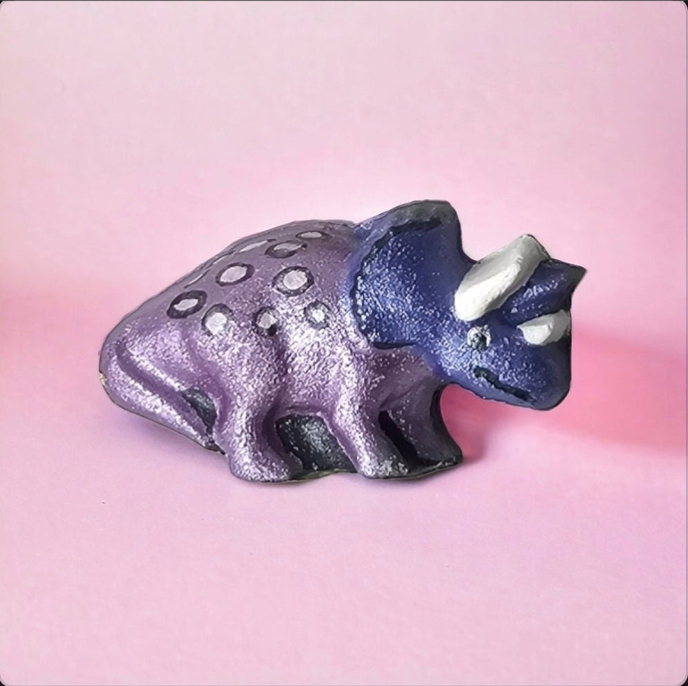 Purple dinosaur figurine on a pink background
